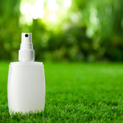 Bottle of insect repellent spray on green grass. space for text