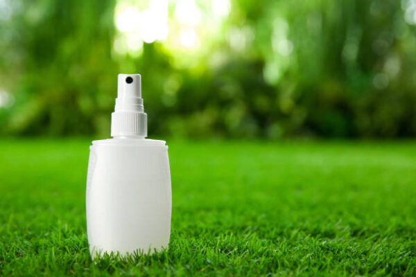 Bottle of insect repellent spray on green grass. space for text